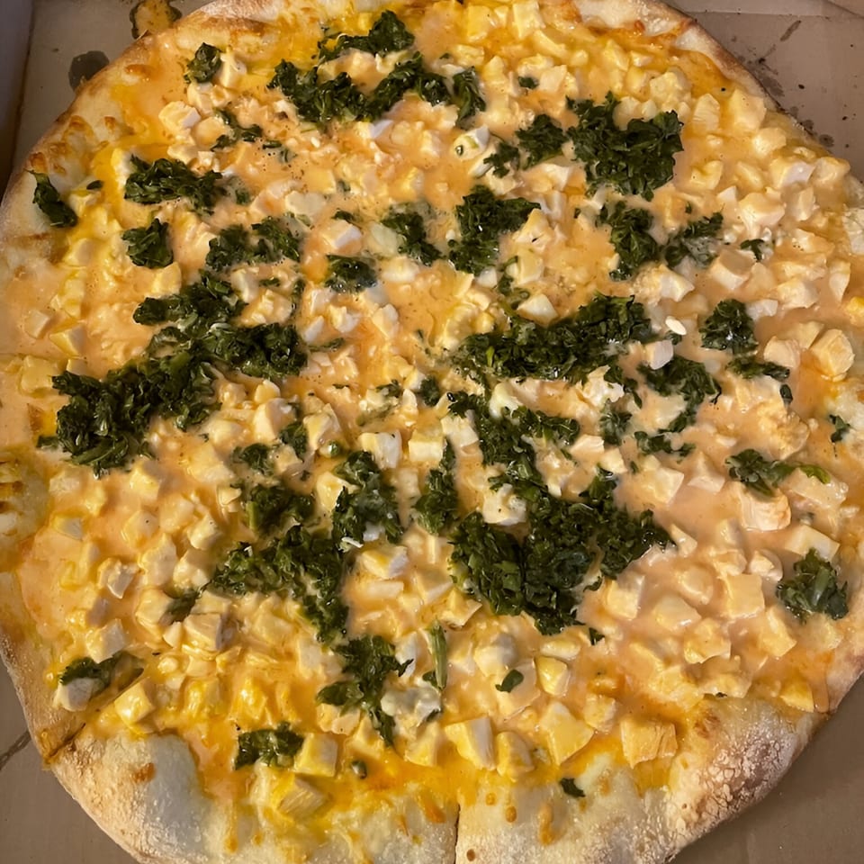A Baci Trattoria & Pizza pie with white and yellow cheese, and green herbs.